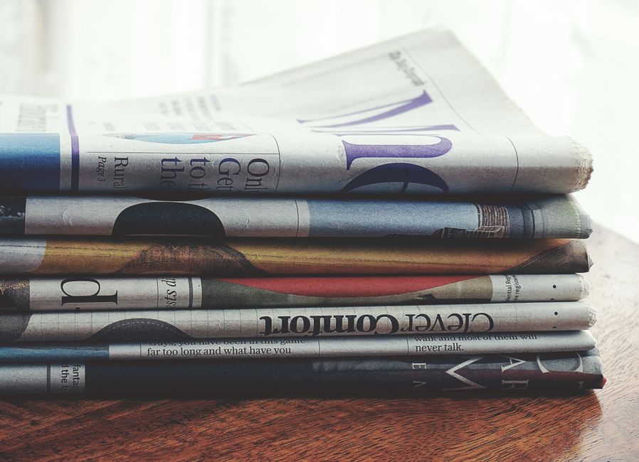 A stack of folded newspapers placed on a wooden table, symbolizing news and information.